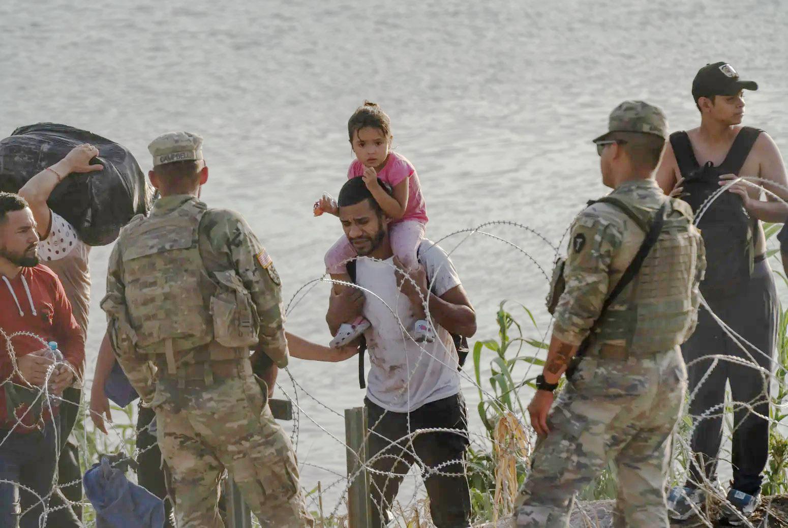 National Guard members tell migrants that they cannot cross the concertina wire barrier and must to walk to another area to surrender to authorities in Eagle Pass on July 29, 2023. Verónica Gabriela Cárdenas/The Texas Tribune