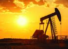 An oil pump industrical machine is seen in the foreground as the sun sets in the back. Adobe Stock