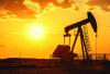 An oil pump industrical machine is seen in the foreground as the sun sets in the back. Adobe Stock